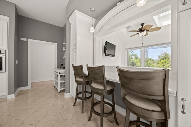 W3318 Lake Forest Ln, Lake Geneva, WI 53147 - kitchen featuring a skylight, a ceiling fan, a breakfast bar, white cabinetry, and stainless steel oven