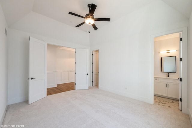unfurnished bedroom with light colored carpet, lofted ceiling, ensuite bath, and ceiling fan