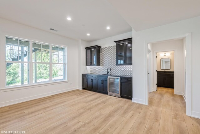 bar with wine cooler, light wood finished floors, recessed lighting, and backsplash