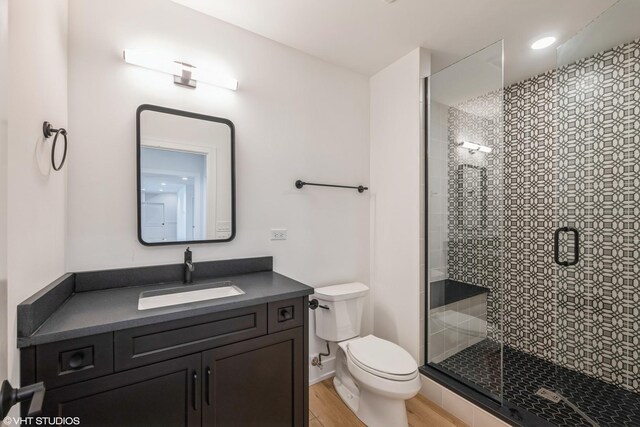 bathroom featuring vanity, a stall shower, and wood finished floors