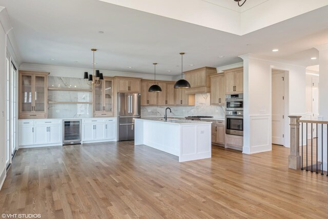 kitchen featuring appliances with stainless steel finishes, wine cooler, tasteful backsplash, light countertops, and light wood finished floors