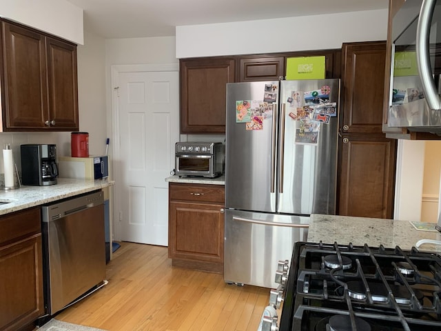 4520 N Austin Ave, Chicago, IL 60630 - kitchen with appliances with stainless steel finishes, light wood-style flooring, light stone counters, and dark brown cabinetry