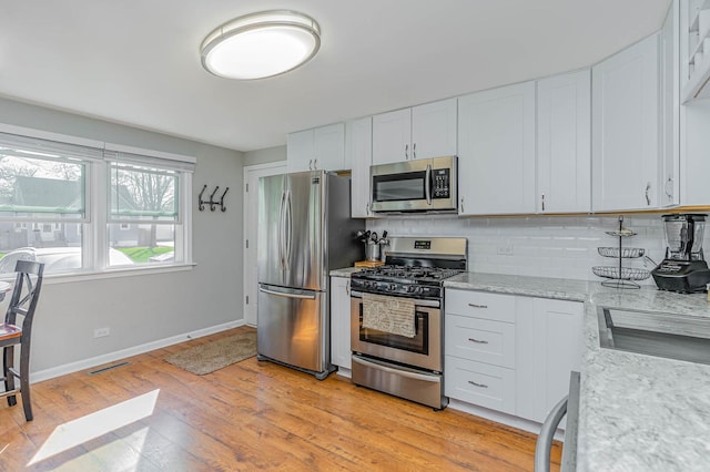 324 N Prospect Dr, Round Lake Park, IL 60073 - kitchen with stainless steel appliances, backsplash, light wood finished floors, white cabinetry, and light stone countertops