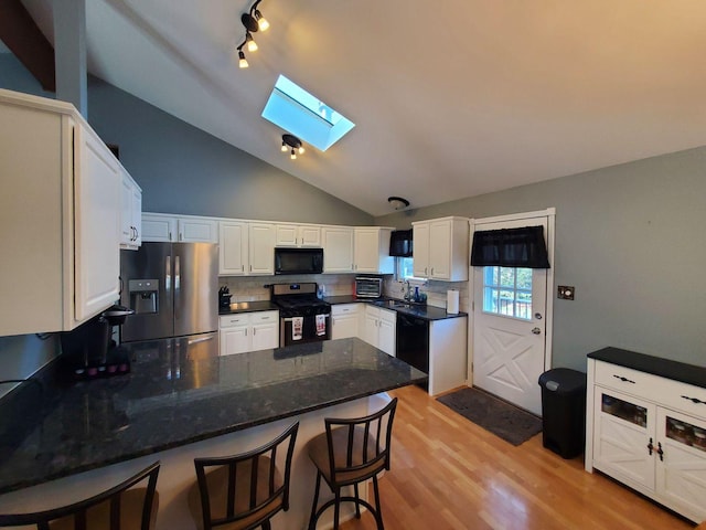 19707 S Skye Dr, Frankfort, IL 60423 - kitchen with black appliances, a skylight, a peninsula, decorative backsplash, and lofted ceiling