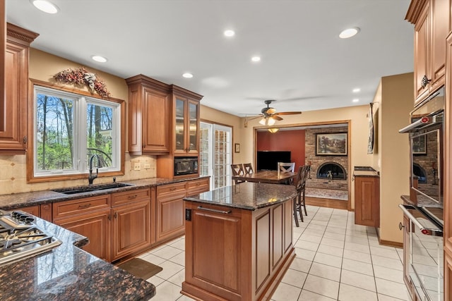 125 Grove Ln, Barrington, IL 60010 - kitchen featuring a brick fireplace, brown cabinets, a center island, backsplash, and light tile patterned floors