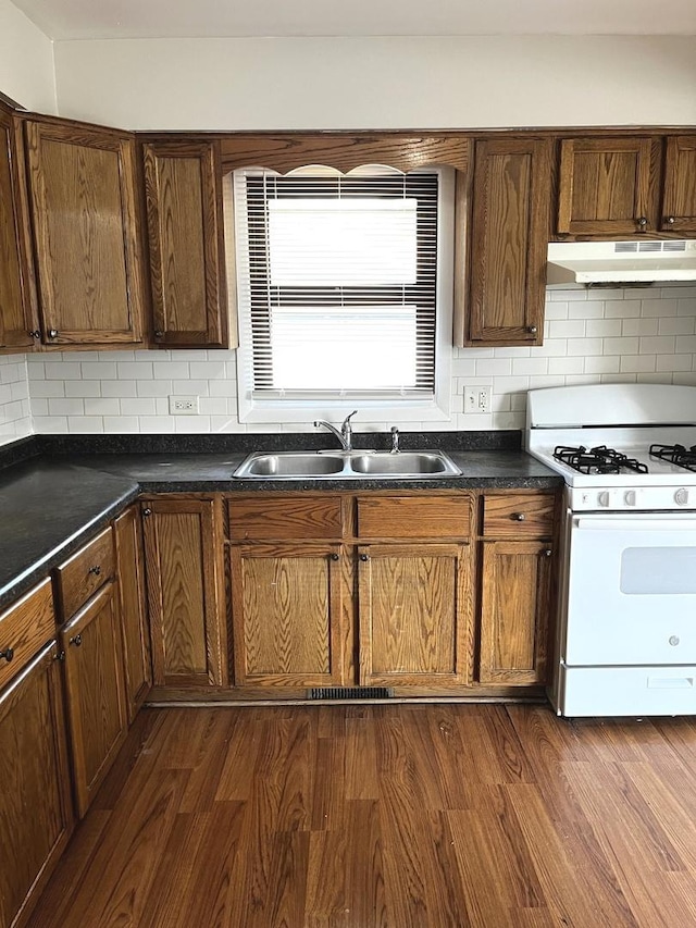 4348 Mann St, Oak Forest, IL 60452 - kitchen featuring white gas range oven, under cabinet range hood, dark countertops, and tasteful backsplash
