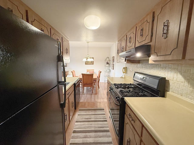 8025 Woodglen Ln Unit 307, Downers Grove, IL 60516 - kitchen with black appliances, under cabinet range hood, light countertops, backsplash, and light wood-style flooring