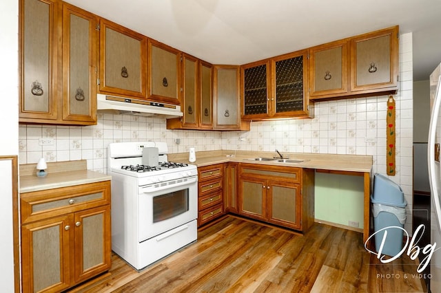 1323 Beverly Dr, Round Lake Beach, IL 60073 - kitchen featuring white range with gas stovetop, under cabinet range hood, light countertops, decorative backsplash, and brown cabinetry
