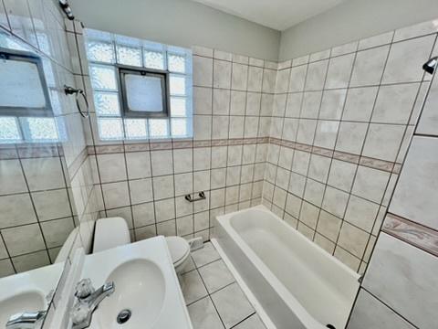 1340 Wesley Ave, Berwyn, IL 60402 - full bath with plenty of natural light, tile patterned floors, tile walls, and shower / bathtub combination
