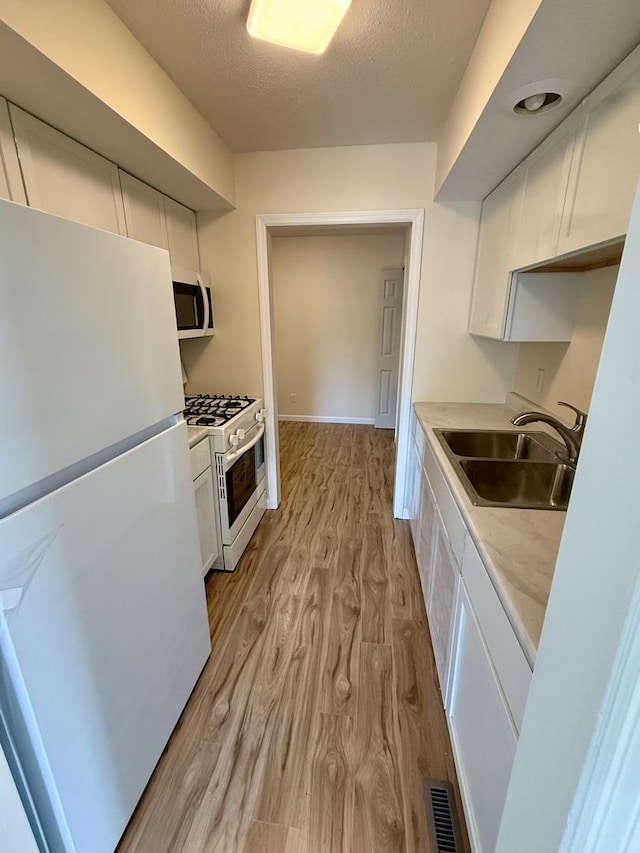 1002 E Harding Dr Unit 303, Urbana, IL 61801 - kitchen featuring white appliances, white cabinetry, light wood-style flooring, light countertops, and a textured ceiling