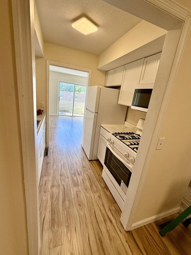 1002 E Harding Dr Unit 303, Urbana, IL 61801 - kitchen with white appliances, light wood-style floors, white cabinets, a textured ceiling, and light countertops