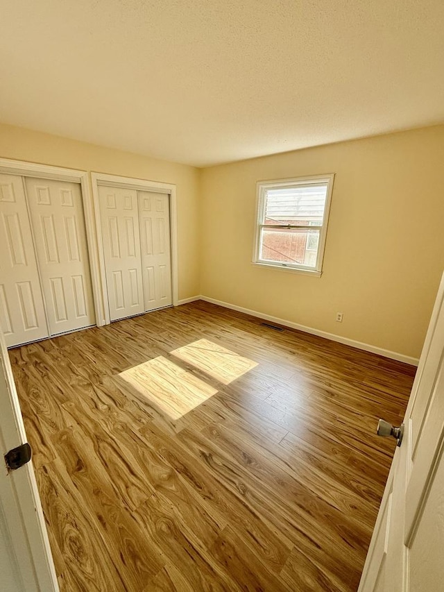 1002 E Harding Dr Unit 303, Urbana, IL 61801 - unfurnished bedroom with two closets and wood finished floors