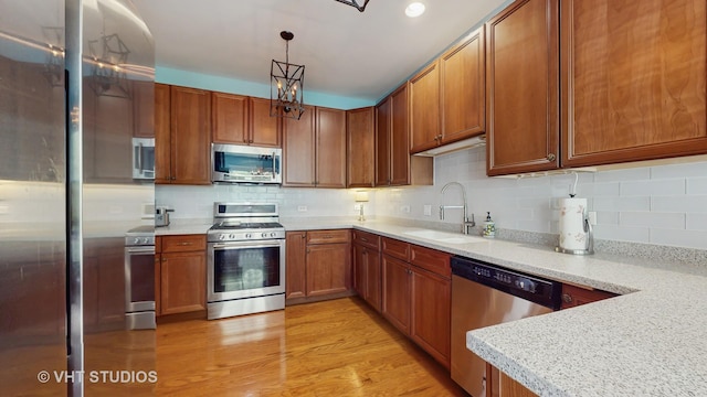 301 W Eagle Ct, Waukegan, IL 60087 - kitchen featuring stainless steel appliances, light countertops, brown cabinetry, decorative backsplash, and light wood-style floors
