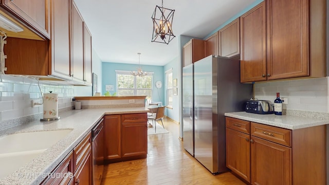301 W Eagle Ct, Waukegan, IL 60087 - kitchen featuring a chandelier, appliances with stainless steel finishes, brown cabinetry, light wood-type flooring, and decorative backsplash