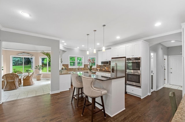 21705 W Hilandale Ct, Kildeer, IL 60047 - kitchen with appliances with stainless steel finishes, arched walkways, white cabinetry, decorative backsplash, and ornamental molding