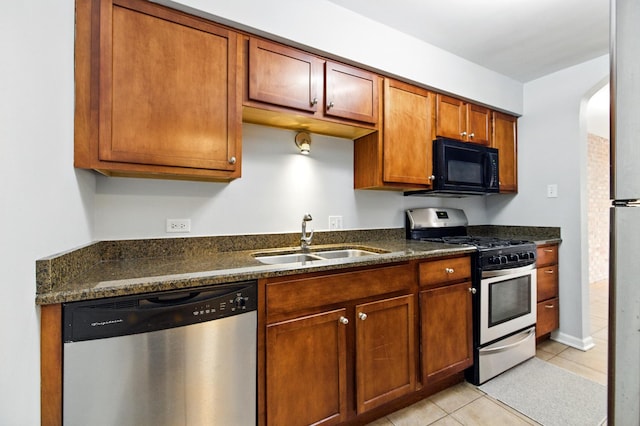 9516 S Kildare Ave Unit 3S, Oak Lawn, IL 60453 - kitchen with stainless steel appliances, light tile patterned floors, brown cabinetry, dark stone counters, and arched walkways