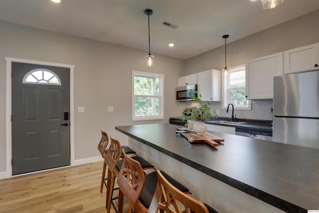 1418 N 6th, Quincy, IL 62301 - kitchen with stainless steel appliances, dark countertops, a kitchen bar, light wood finished floors, and plenty of natural light