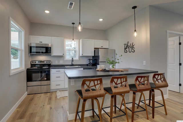 1418 N 6th, Quincy, IL 62301 - kitchen featuring appliances with stainless steel finishes, light wood-type flooring, a breakfast bar, white cabinets, and recessed lighting