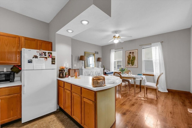 611 W White St, Champaign, IL 61820 - kitchen featuring freestanding refrigerator, a peninsula, light countertops, ceiling fan, and brown cabinetry