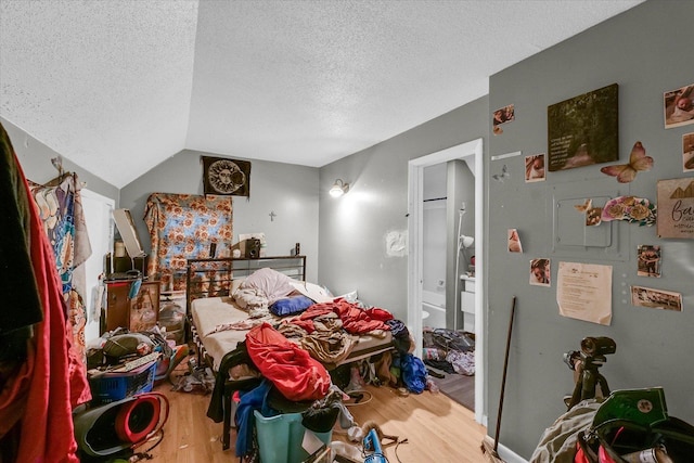 611 W White St, Champaign, IL 61820 - bedroom with wood finished floors, a textured ceiling, freestanding refrigerator, connected bathroom, and vaulted ceiling