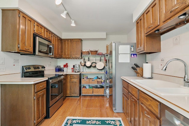 434C Woodview Rd Unit C, Lake Barrington, IL 60010 - kitchen featuring appliances with stainless steel finishes, decorative backsplash, brown cabinetry, and light wood finished floors