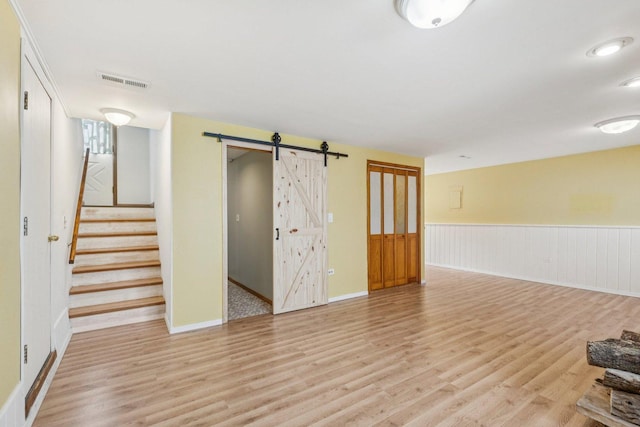 1228 N Lake Shore Dr, Round Lake Beach, IL 60073 - unfurnished room with a barn door, light wood finished floors, stairway, and wainscoting