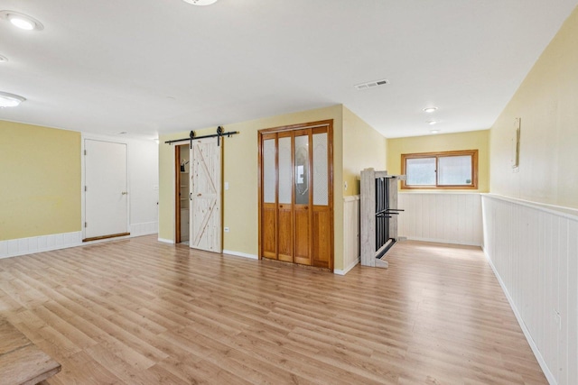 1228 N Lake Shore Dr, Round Lake Beach, IL 60073 - unfurnished living room with a barn door, light wood-style flooring, a wainscoted wall, and a fireplace