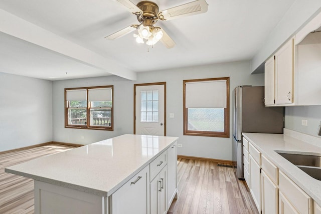 1228 N Lake Shore Dr, Round Lake Beach, IL 60073 - kitchen with light wood-style floors, a ceiling fan, freestanding refrigerator, a center island, and light stone countertops
