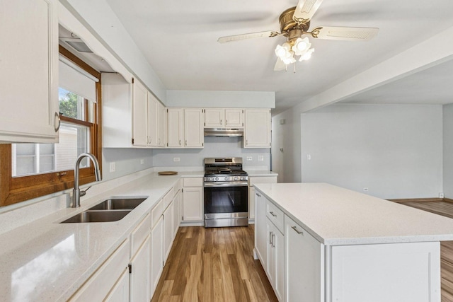 1228 N Lake Shore Dr, Round Lake Beach, IL 60073 - kitchen with stainless steel gas range oven, under cabinet range hood, light wood-type flooring, white cabinetry, and ceiling fan