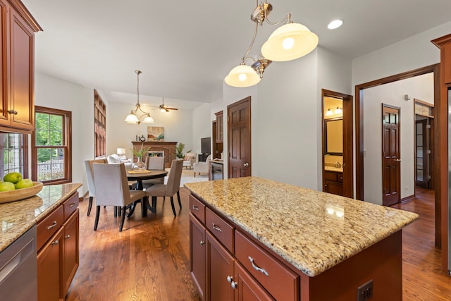 609 Spruce Ct, Oswego, IL 60543 - kitchen featuring stainless steel dishwasher, a kitchen island, dark wood-type flooring, hanging light fixtures, and a fireplace