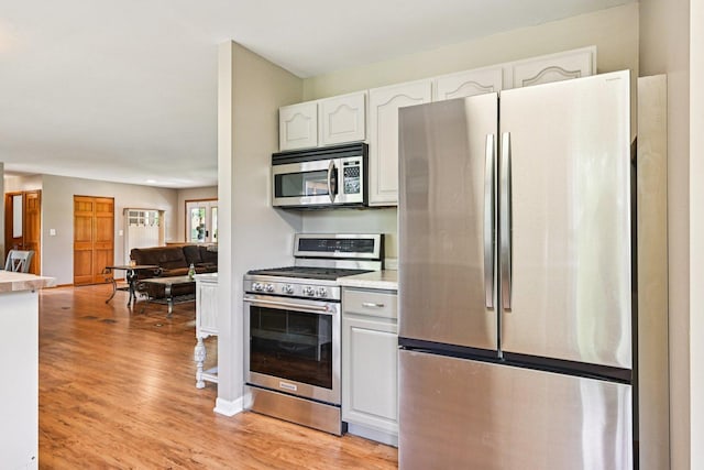 6180 Elm St, Union, IL 60180 - kitchen featuring appliances with stainless steel finishes, light countertops, white cabinetry, light wood finished floors, and open floor plan