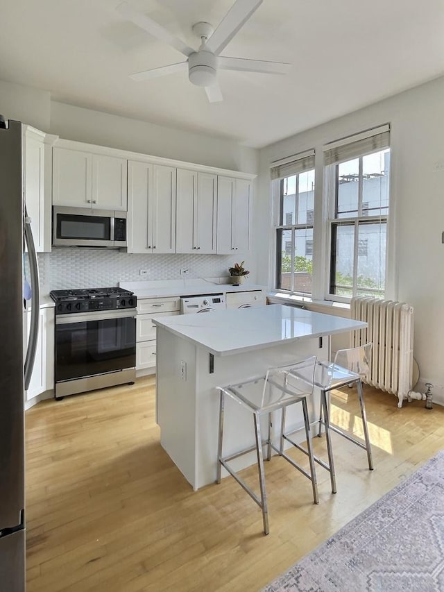 2680 N Burling St Unit 3S, Chicago, IL 60614 - kitchen featuring stainless steel appliances, radiator, tasteful backsplash, white cabinets, and light countertops