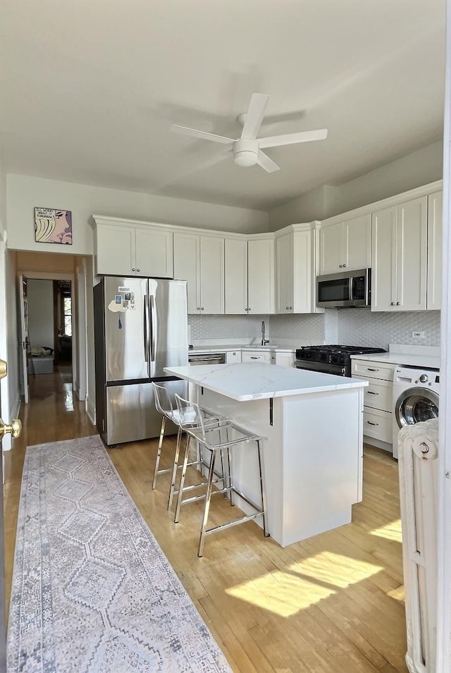 2680 N Burling St Unit 3S, Chicago, IL 60614 - kitchen with appliances with stainless steel finishes, washer / dryer, ceiling fan, light countertops, and white cabinetry