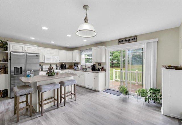 1707 Lydia Ct, Urbana, IL 61802 - kitchen featuring white appliances, white cabinetry, recessed lighting, a breakfast bar area, and a center island