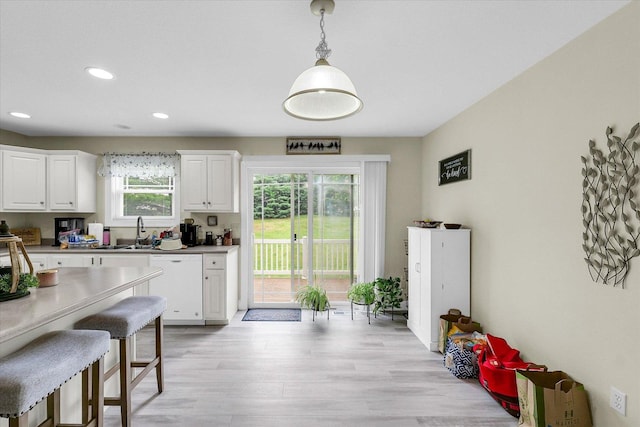 1707 Lydia Ct, Urbana, IL 61802 - kitchen featuring dishwasher, white cabinets, recessed lighting, light wood-style floors, and a breakfast bar