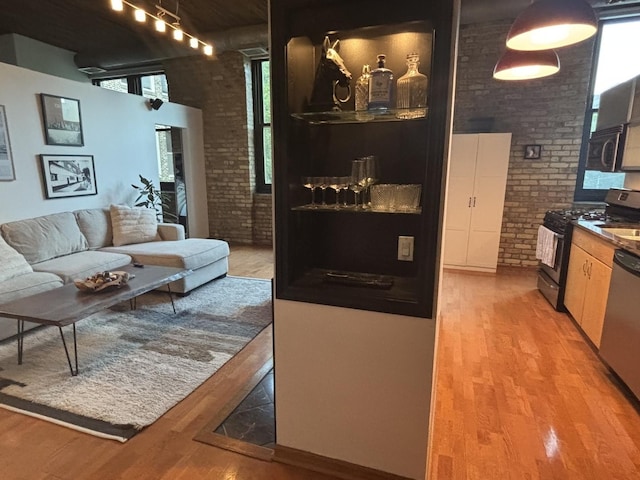 2510 N Wayne Ave Unit 203, Chicago, IL 60614 - living area featuring brick wall, light wood-type flooring, rail lighting, and a towering ceiling