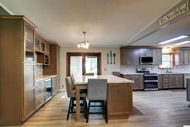701 Dudley St, Liberty, IL 62347 - kitchen featuring appliances with stainless steel finishes, a chandelier, wine cooler, a center island, and decorative backsplash