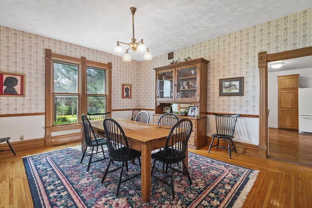 466 Quail Trap Rd, Caledonia, IL 61011 - dining area featuring a chandelier, wainscoting, wallpapered walls, and wood finished floors