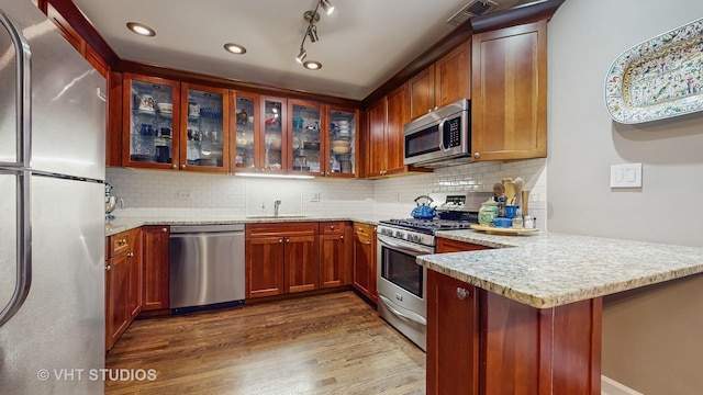 4550 N Malden St Unit 1W, Chicago, IL 60640 - kitchen with stainless steel appliances, a peninsula, dark wood-style flooring, glass insert cabinets, and backsplash
