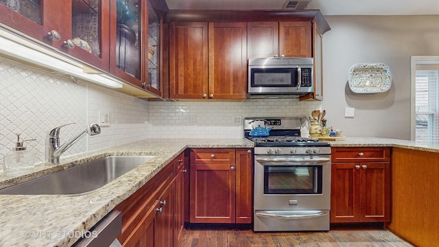 4550 N Malden St Unit 1W, Chicago, IL 60640 - kitchen featuring appliances with stainless steel finishes, light stone countertops, dark wood-style floors, glass insert cabinets, and tasteful backsplash