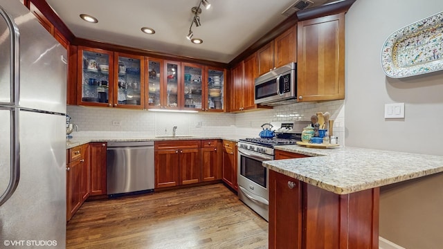 4550 N Malden St Unit 1W, Chicago, IL 60640 - kitchen with stainless steel appliances, a peninsula, dark wood-style flooring, glass insert cabinets, and tasteful backsplash