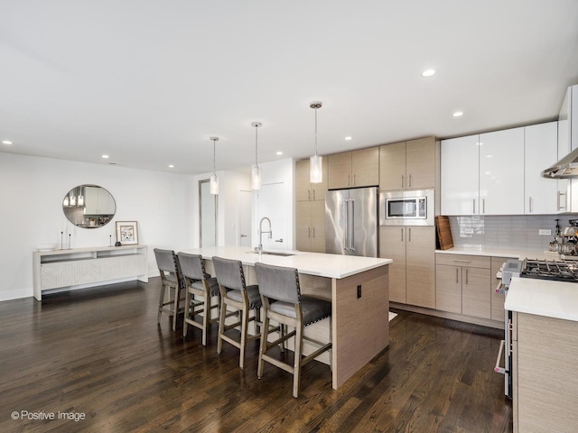 2707 W Belmont Ave Unit 4W, Chicago, IL 60618 - kitchen featuring stainless steel appliances, decorative backsplash, light countertops, dark wood-type flooring, and a kitchen breakfast bar