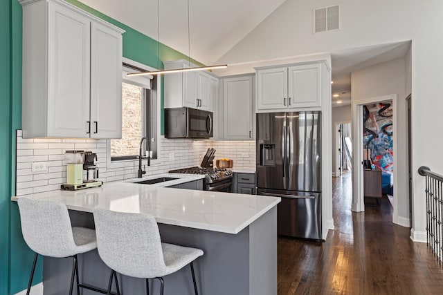 3047 N Racine Ave Unit 3, Chicago, IL 60657 - kitchen with appliances with stainless steel finishes, a peninsula, light stone counters, lofted ceiling, and backsplash