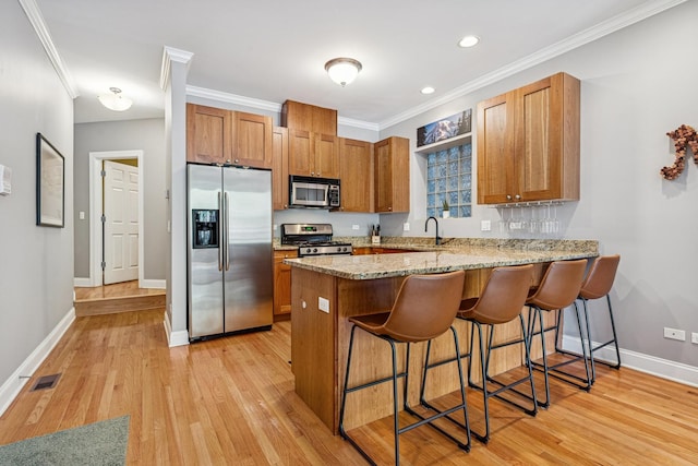 4660 N Winthrop Ave Unit 1N, Chicago, IL 60640 - kitchen featuring appliances with stainless steel finishes, crown molding, a peninsula, brown cabinets, and a breakfast bar