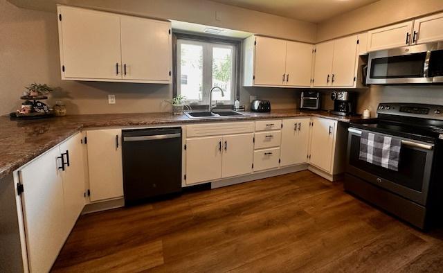 1700 Sunset Dr, Mendota, IL 61342 - kitchen with stainless steel appliances, white cabinets, dark wood-type flooring, and dark countertops