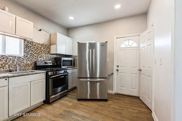 32 W 109th Pl, Chicago, IL 60628 - kitchen featuring appliances with stainless steel finishes, tasteful backsplash, wood finished floors, white cabinetry, and recessed lighting