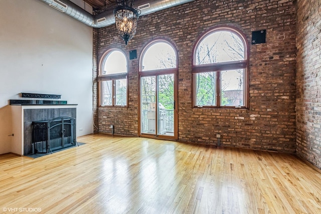 920 W Sheridan Rd Unit 305, Chicago, IL 60613 - unfurnished living room with a towering ceiling, brick wall, wood finished floors, a chandelier, and a fireplace with flush hearth