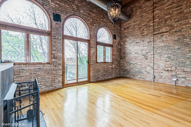 920 W Sheridan Rd Unit 305, Chicago, IL 60613 - unfurnished living room with brick wall, a towering ceiling, wood finished floors, and plenty of natural light