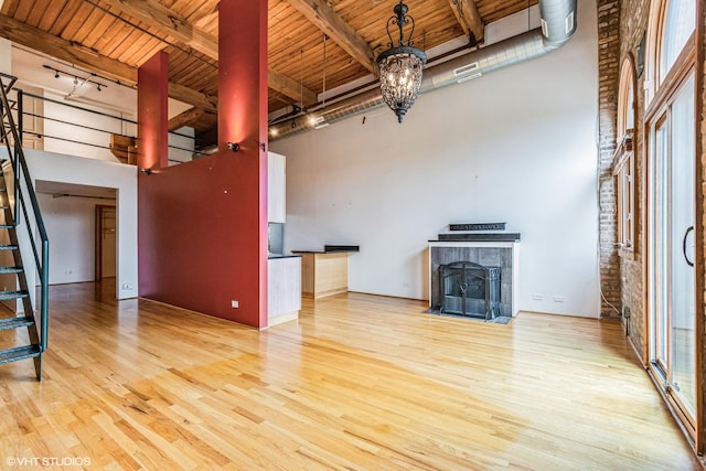 920 W Sheridan Rd Unit 305, Chicago, IL 60613 - unfurnished living room featuring a wood ceiling with exposed beams, wood finished floors, a towering ceiling, stairway, and a chandelier