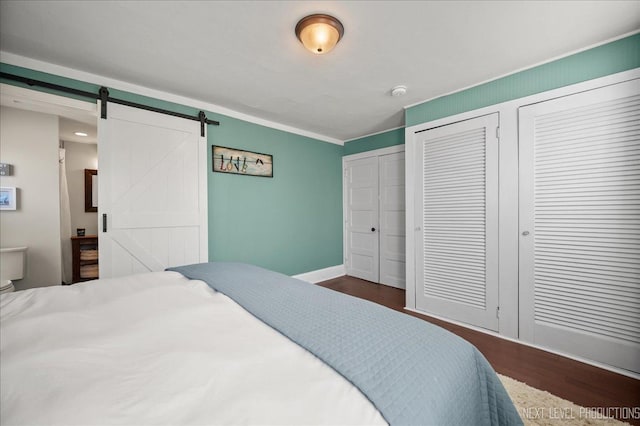 704 Cedar Ave, Saint Charles, IL 60174 - bedroom featuring a barn door, dark wood-style floors, two closets, and ornamental molding
